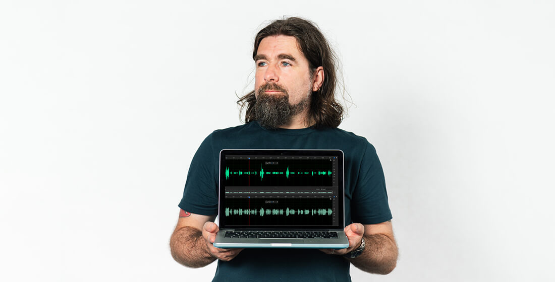 Rob Bee from B Double E holding a laptop with audio compression showing on the screen.