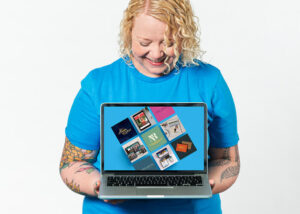 Helen Bee from B Double E looking down at a laptop with her voiceover branding and logo designs on the screen.