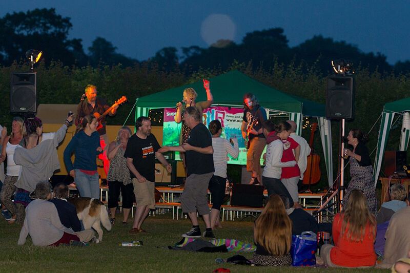 Rob, Dave & Helen playing at a festival, crowd dancing.