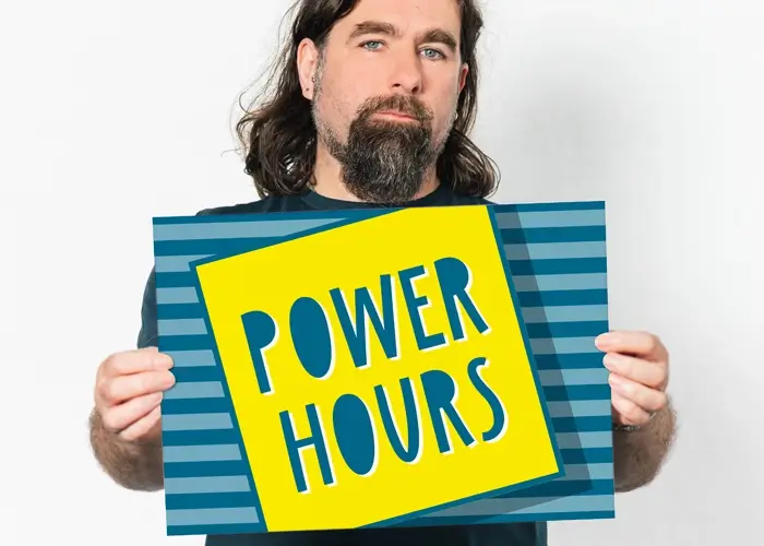 Rob Bee from B double E holding an A3 card that says 'power hour'. He's wearing a dark blue t-shirt and standing in front of a plain white background.